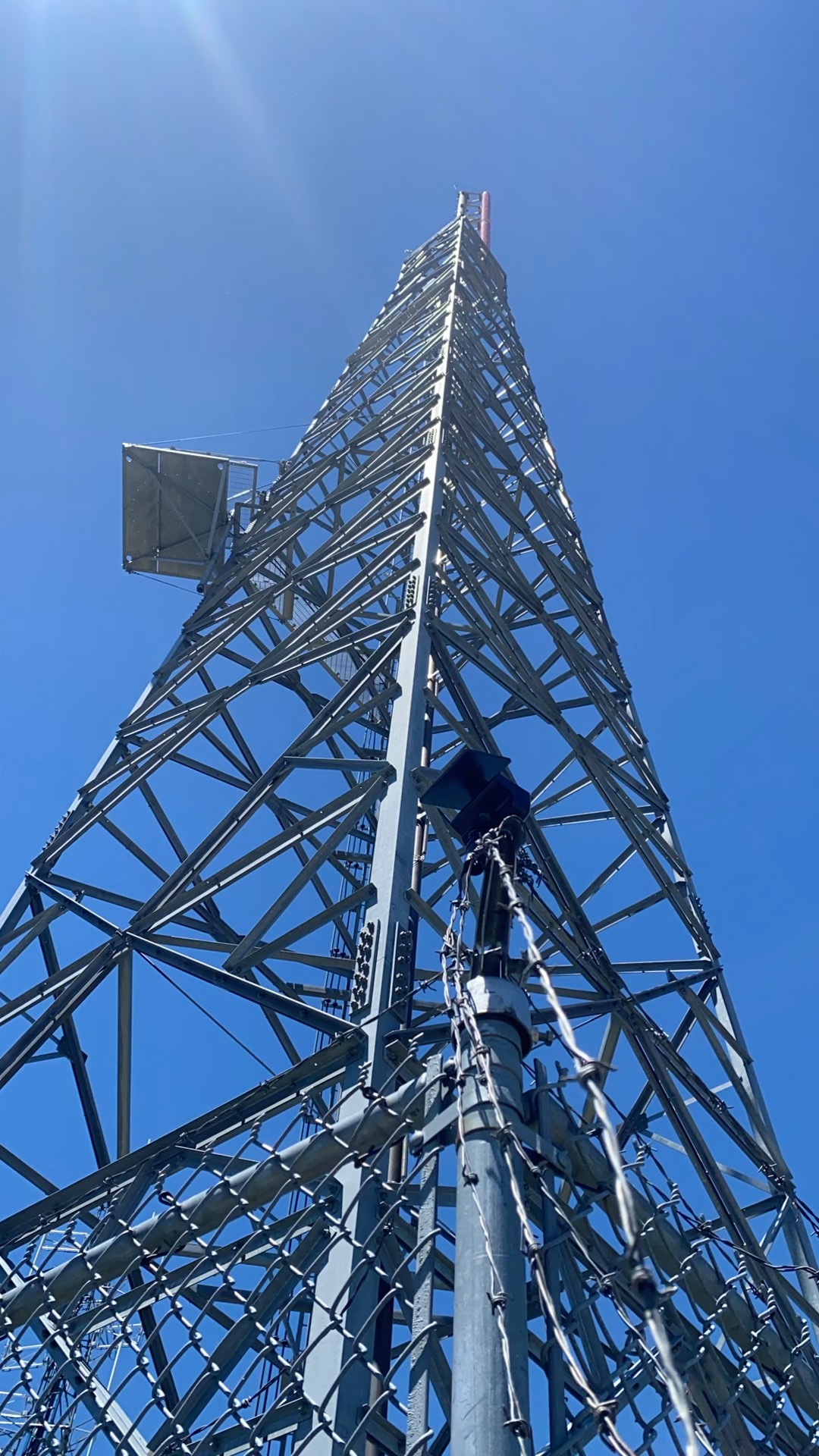 Lattice tower rising above the barbed-wire perimeter fence at Peavine