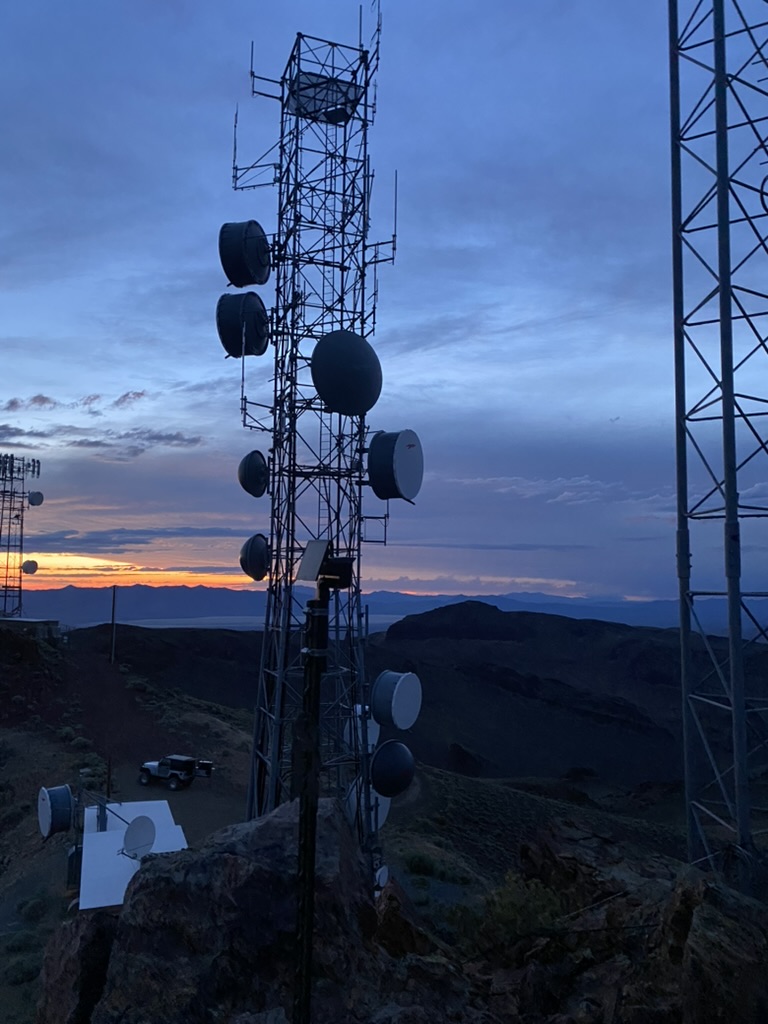 Lattice tower and Jeep on Toulon Peak with sunset over the valley