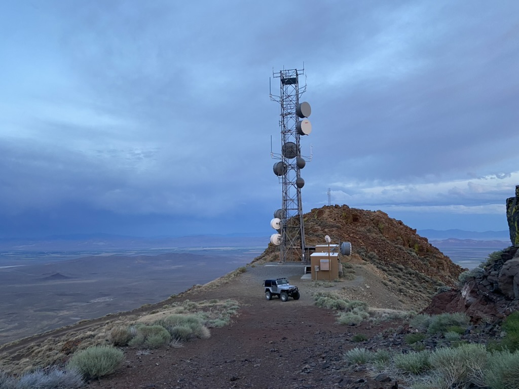 Wide view of the Toulon Peak ridge, Jeep, and tower site under storm clouds at dusk