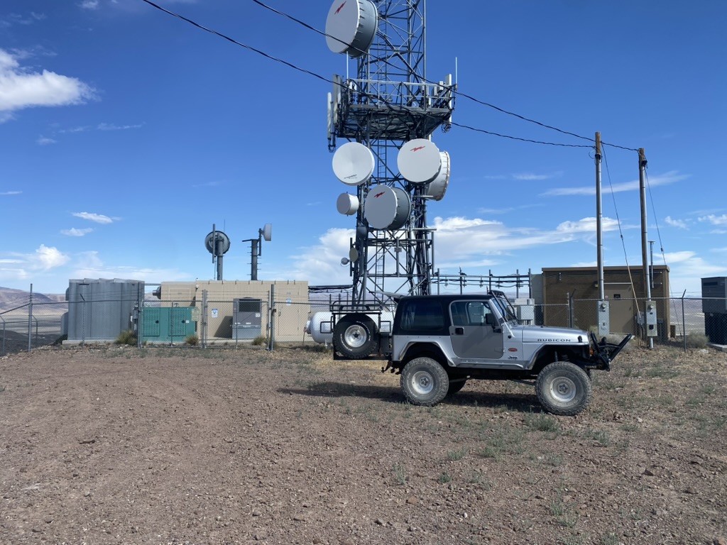 Jeep at the High Sierra Communications compound on Desert Peak with microwave dishes on the lattice tower