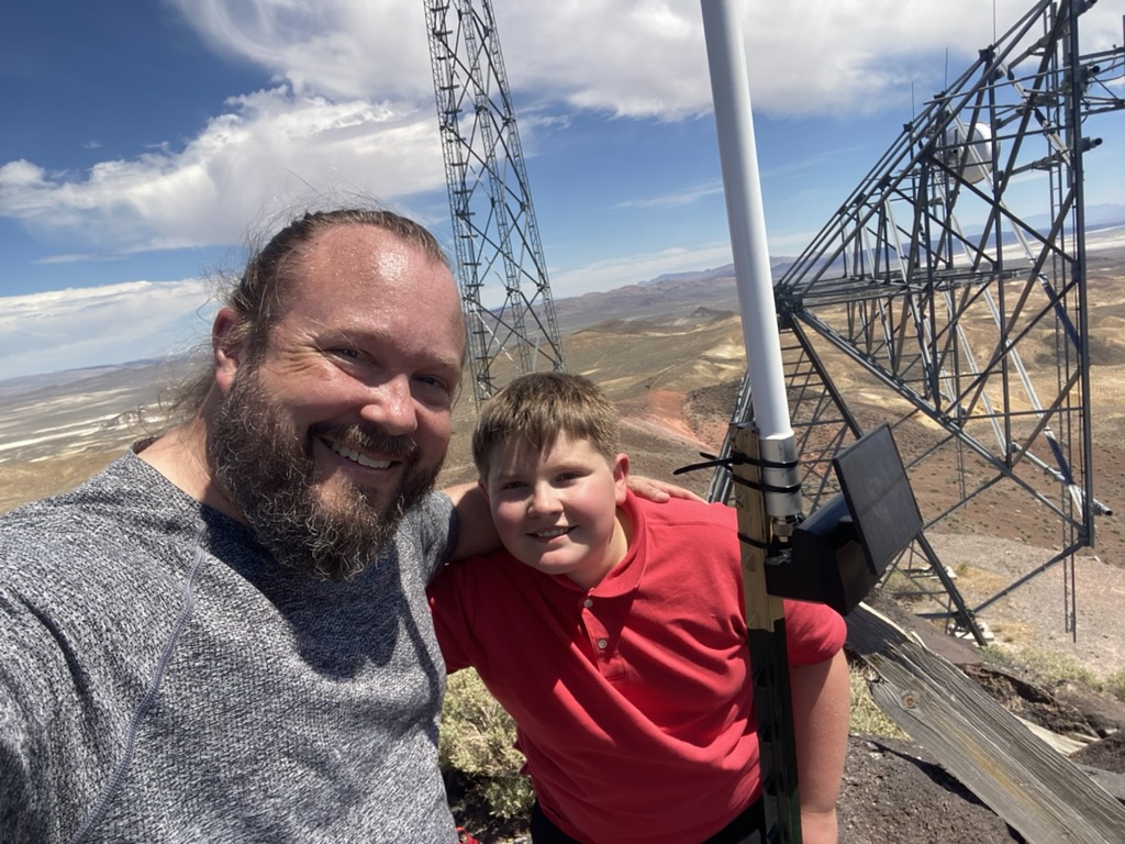 Ben and Sam at Desert Peak with a mesh node, lattice tower, and Carson Sink playas in the background
