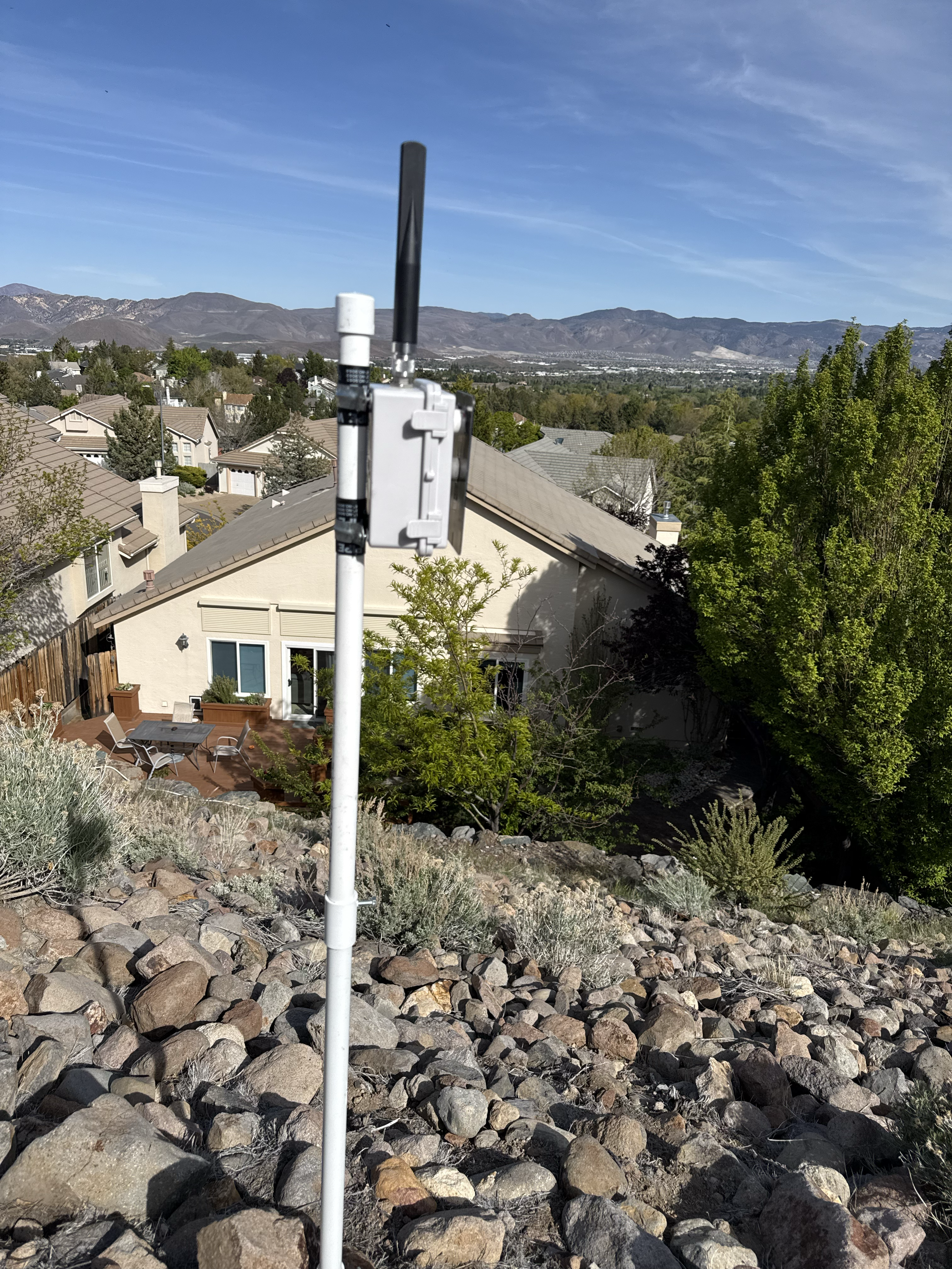 Gray IP67 enclosure on a pole above a Reno neighborhood with mountains in the background