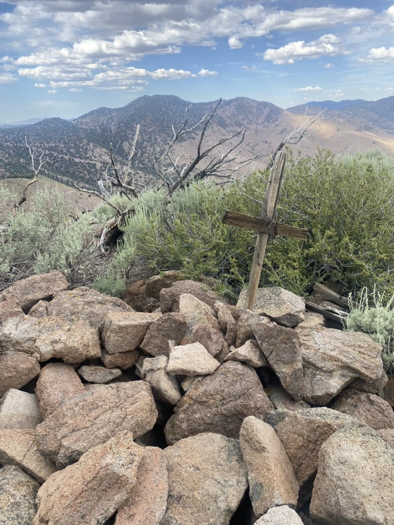 Weathered wooden cross and rock cairn on the Flowery Peak summit