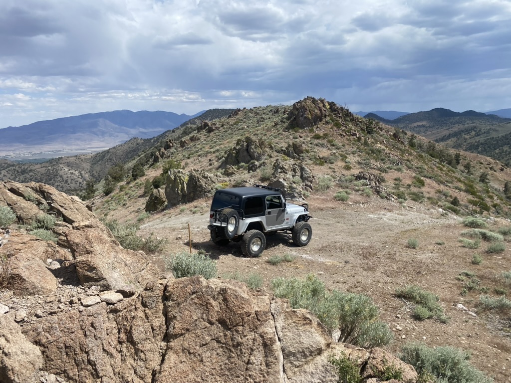 Silver Jeep parked on the rocky Flowery Peak summit with Virginia City visible in the valley below