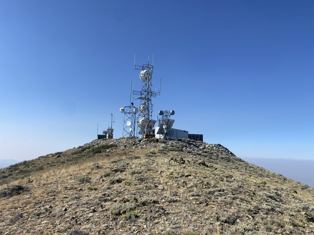 Microwave towers and solar panels at the Fox Mountain radio compound, smoke haze on the horizon
