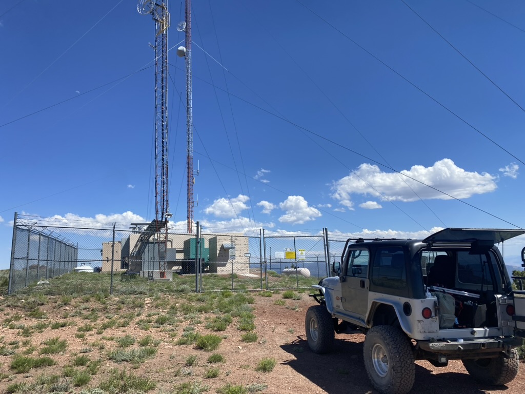 Silver Jeep Wrangler at the McClellan Peak radio compound with tailgate open and gear in back