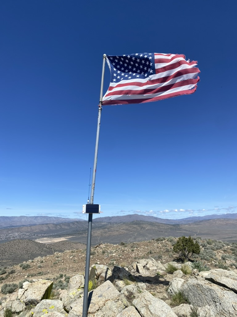 ME0002 on the Spanish Benchmark flagpole, orange zip-tie mount and tattered flag above the basin